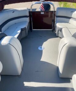 Interior view looking toward the stern of a Starcraft pontoon boat, featuring two light gray upholstered captain's chairs, a steering console, and additional rear lounge seating under a maroon bimini top.